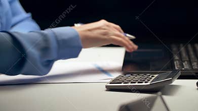 Woman with calculator and laptop at night office