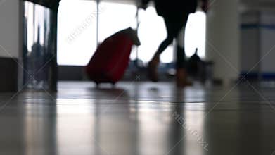 Anonymous people walking through an airport terminal with suitcases, bags and baggage