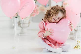Cute six year old girl in pink dress with pink balloons in the shape of heart