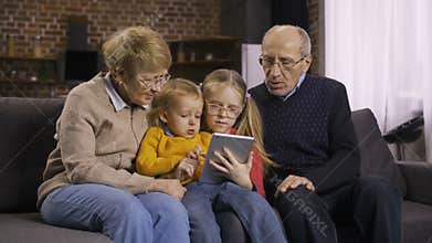 Family using tablet pc on sofa together at home
