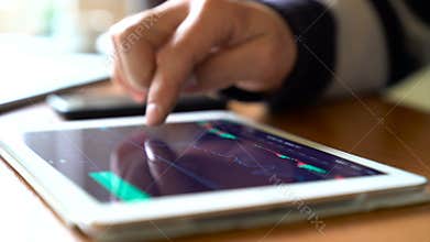 Businessman in the office works on tablet pc with stock charts.