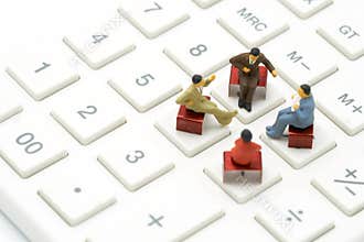 Miniature 4 people sitting on red staples placed on a white calculator. meeting or Discussion as background business concept with