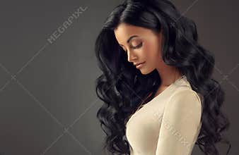 Young black haired woman with voluminous, shiny and wavy hair.