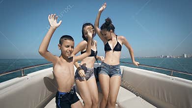 Happy teens are having the time of their lives dancing on a boat