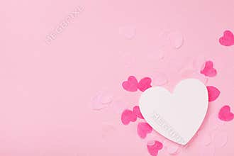 White wooden heart and paper hearts on pink pastel background top view. Greeting card for Valentines, Woman or Mothers Day.