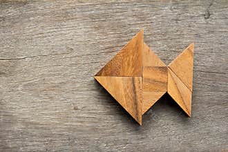 Chinese tangram puzzle in fish shape on wood background