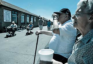 Elderly couple sip tea as pensioners cruise by on motorised carts