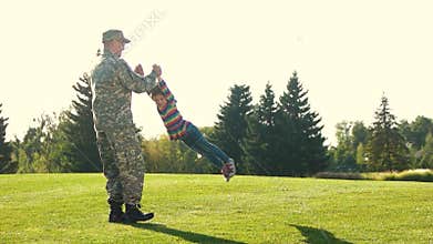 Military father playing and spinning with his daughter in the park.