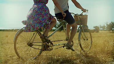Couple man and woman riding a bicycle tandem on summer field and haystacks