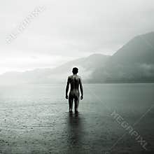 Young naked man in lake