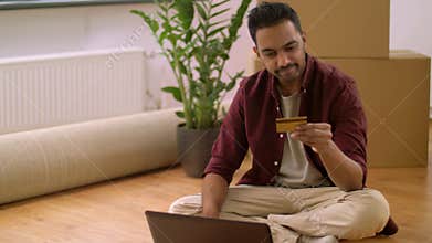 Man with laptop shopping online at new home