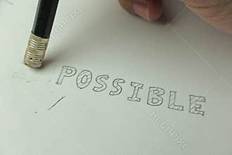 Changing the word impossible to possible with a pencil eraser