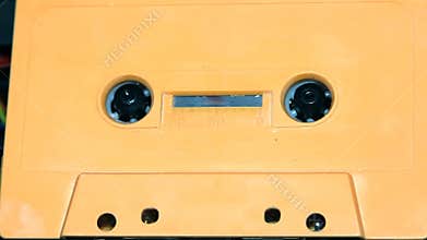 Orange audio cassette tape with a blank label