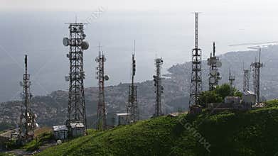 Aerial view of telecommunications towers with antennas and cityscape in the background