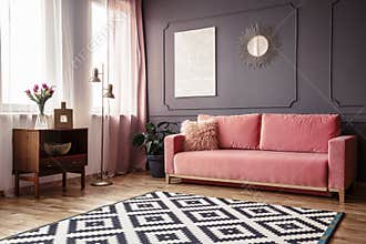 Side angle of a living room interior with a powder pink sofa, pa