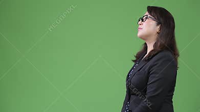 Profile view of mature beautiful Asian businesswoman against green background