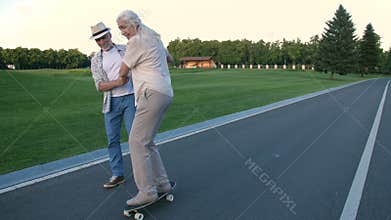 Husband teaching wife to skateboard in summer park