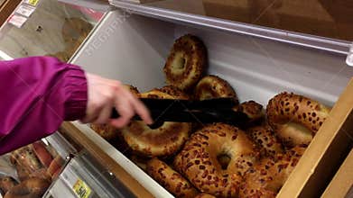Motion of woman selecting bagel on bulk food section inside superstore