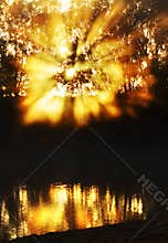 Spectacular sunrise sunbeams bursting through mist reflecting river water