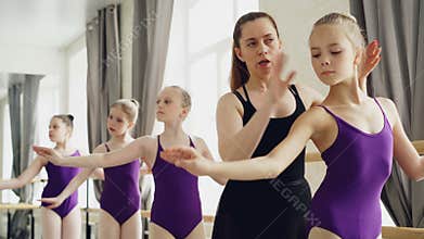 Starting ballet dancers are practising arm movements during ballet class in studio. Tutor professional ballerina