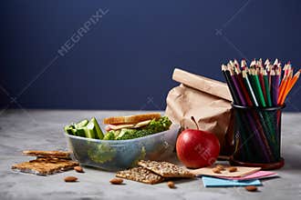 Back to School concept, school supplies, biscuits, packed lunch and lunchbox on white desk, selective focus, close-up.