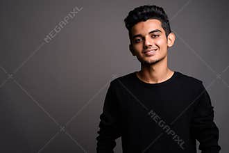 Young Indian man against gray background
