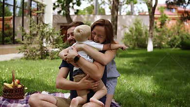 Family idyll. Happy child running to his parents in a blurred perspective. Close up of young couple hugging his little
