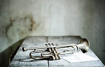 A beautiful jazz trumpet from the 40s with a new musical score over an old wooden table