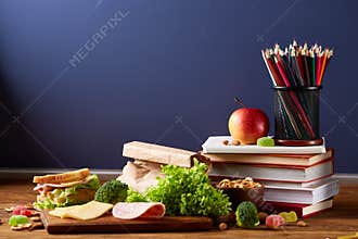 Back to School concept, school supplies, biscuits and lunchbox on wooden desk, selective focus, close-up.