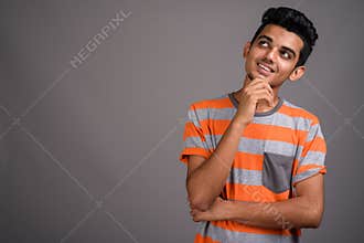 Young Indian man against gray background