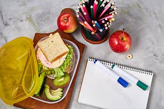 Back to School concept, school supplies, biscuits, packed lunch and lunchbox over white chalkboard, selective focus.