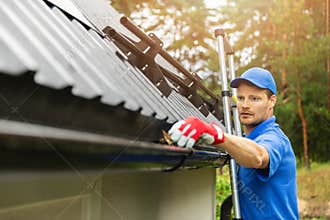 Worker cleaning house gutter