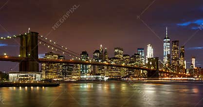 Lower Manhattan Financial District skyscrapers, Brooklyn Bridge, and East River with passing clouds at twilight. Manhattan, New Yo