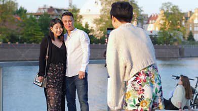 Asians lovers tourists make photos on mobile phone on background of town river
