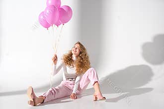 smiling girl with bundle of pink balloons sitting
