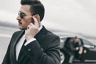 handsome bodyguard of businessman listening message