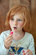 The girl paints lips with brilliance