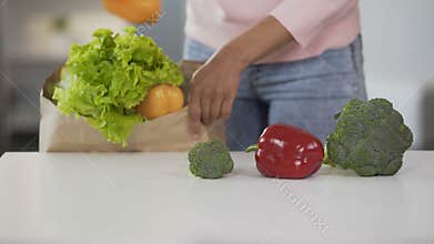 Lady taking vegetables from grocery bag, putting on table, healthy eating, diet