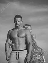 Couple in love on sunny summer day. Bodybuilding and fitness. Man and woman posing on blue sky. Bodybuilder with