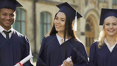 College student in graduation outfit with diplomas smiling, education abroad