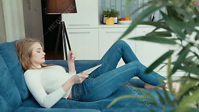 Young woman using tablet computer while sitting on sofa.