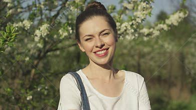 Smiling beautiful woman near blossoming tree