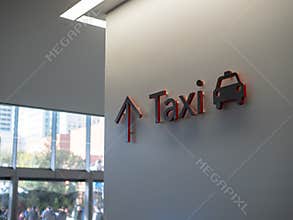 Red and black taxi sign hung on wall on modern building