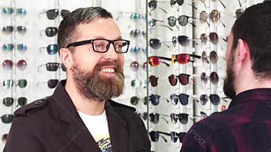 Mature male customer talking to the optometrist while choosing new glasses