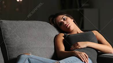 Sad teen looking away on a couch at home