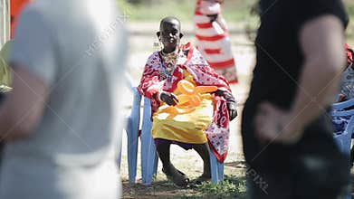 KENYA, KISUMU - MAY 20, 2017: Old African woman from local maasai tribe sitting on chair and hold balloon.