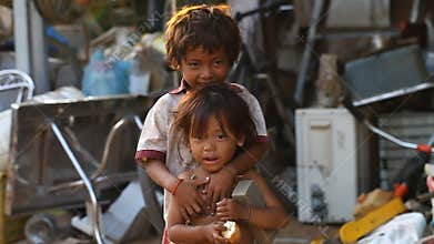 Siam Reap, Cambodia - January 14, 2017: A homeless boy with his young sister living in a house from empty boxes and