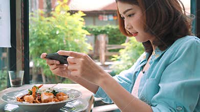 A young woman taking photo of spaghetti food on smartphone, photographing meal with mobile camera.