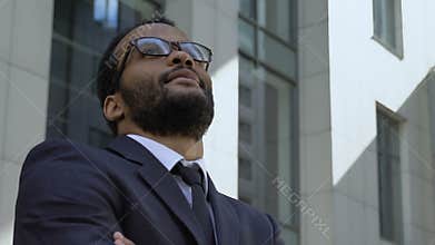 Successful afro-american businessman standing near office building, closeup