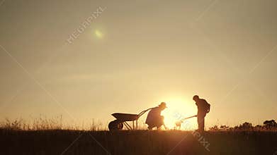 Happy family father and son harvesting in the field at sunset